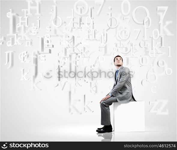 Man on cube. Young handsome businessman sitting on white cube