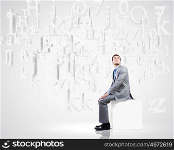 Man on cube. Young handsome businessman sitting on white cube