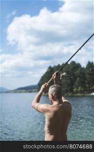 Man on fishing with rod. Mountain lake
