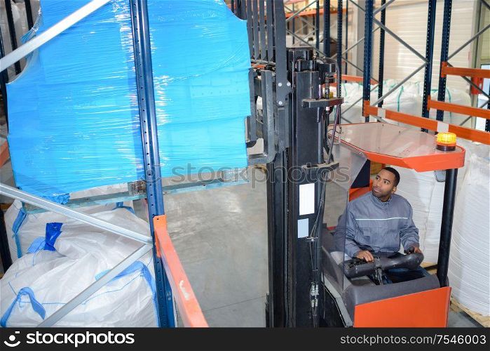 man on forklift loader loading boxes at warehouse
