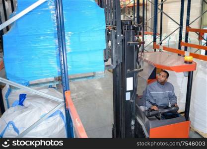 man on forklift loader loading boxes at warehouse