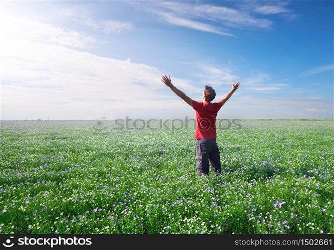 Man on green and blossom meadow of flax reach to sun in deep blue sky. Conceptual scene.