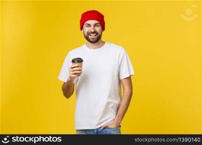 Man on isolated vibrant yellow color taking a coffee in takeaway paper cup and smiling because he will start the day well. Man on isolated vibrant yellow color taking a coffee in takeaway paper cup and smiling because he will start the day well.