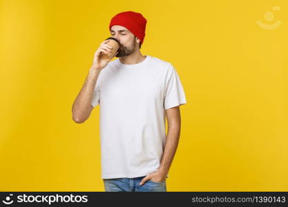 Man on isolated vibrant yellow color taking a coffee in takeaway paper cup and smiling because he will start the day well. Man on isolated vibrant yellow color taking a coffee in takeaway paper cup and smiling because he will start the day well.