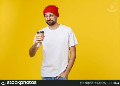 Man on isolated vibrant yellow color taking a coffee in takeaway paper cup and smiling because he will start the day well. Man on isolated vibrant yellow color taking a coffee in takeaway paper cup and smiling because he will start the day well.