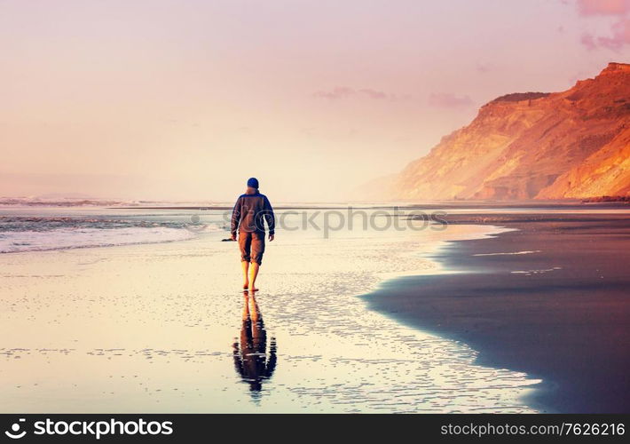 Man on ocean beach at sunset. Vacation concept background.