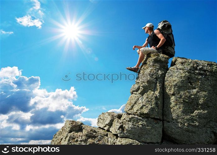 Man on peak of mountain sitting on the rock