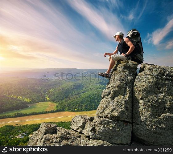Man on peak of mountain sitting on the rock
