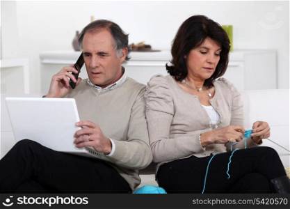 Man on phone and woman knitting at home