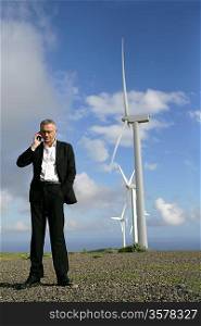 Man on phone in front of wind turbines