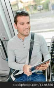 man on public transport, holding tablet