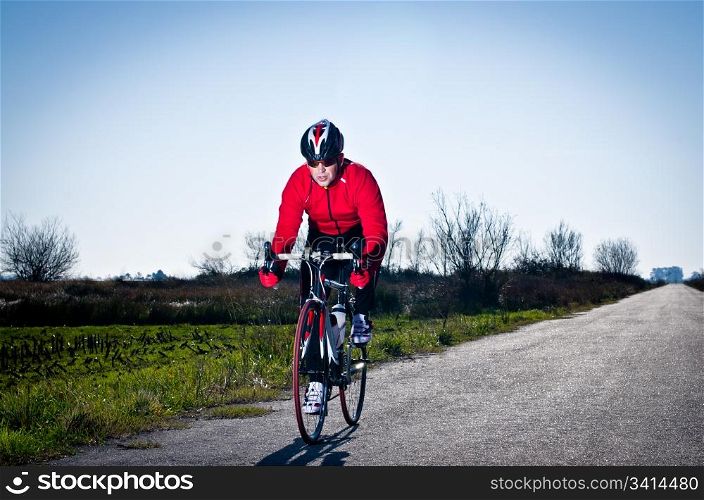 Man on road bike riding down open country road.
