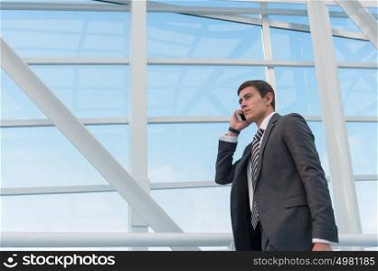 Man on smart phone - young business man in airport. Casual urban professional businessman using smartphone smiling happy inside office building or airport. Handsome man wearing suit jacket indoors.