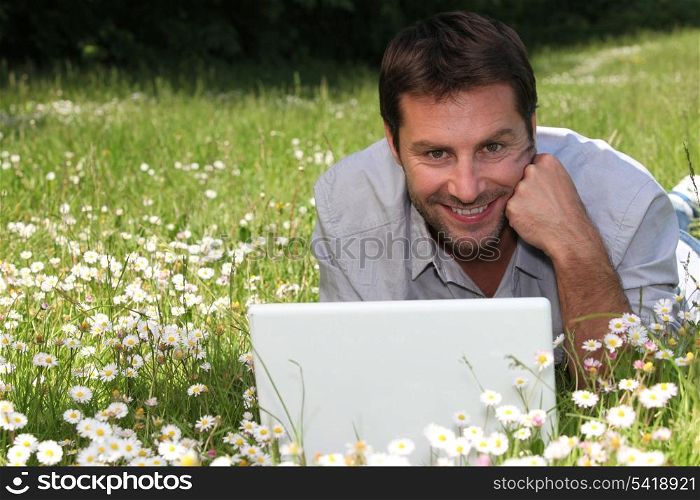man on the grass with laptop