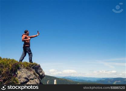 Man on the mountain top taking selfie by cell phone