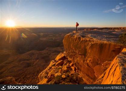 Man on the mountains cliff at sunrise. Hiking scene.