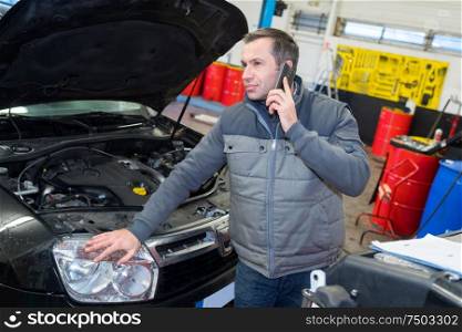 man on the phone with opened car hood