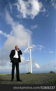 Man on the telephone next to a wind turbine
