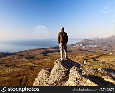 Man on the top of the mountain looking at full moon