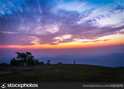 Man on top hill beautiful sky sunset or sunrise with clouds dramatic colorful blue purple and yellow sky twilight - Landscape on top hill view scenery
