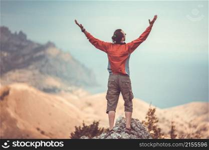 Man on top of mountain holding arms up. Man on top