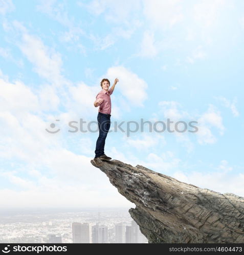 Man on top. Young man balancing on one leg on edge of rock