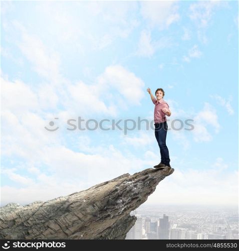 Man on top. Young man balancing on one leg on edge of rock