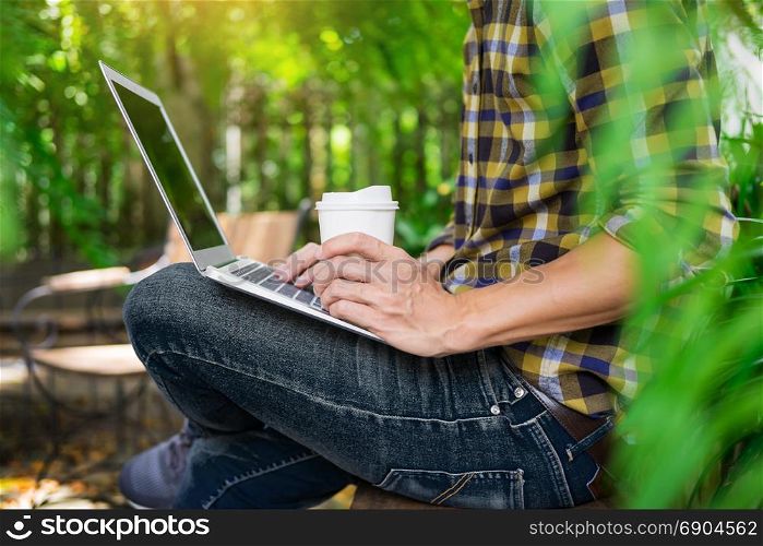 man on week-end working on laptop computer outdoor in a park garden during a sunny summer day
