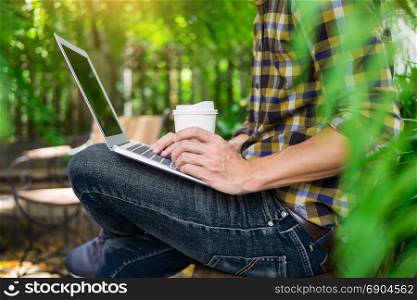 man on week-end working on laptop computer outdoor in a park garden during a sunny summer day