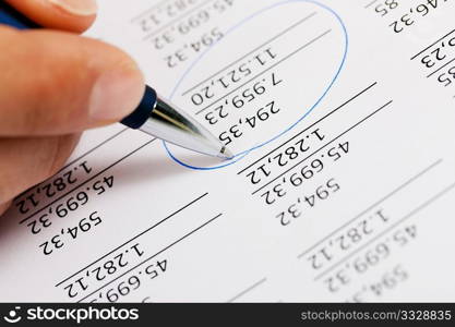 Man (only hand to be seen, presumably an accountant) working on a document with numbers