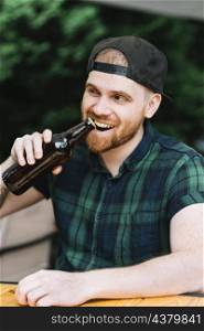 man opening beer bottle cap with his teeth