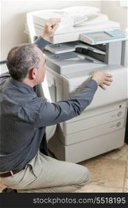 Man opening photocopier in office. Business man opening photocopy machine in office