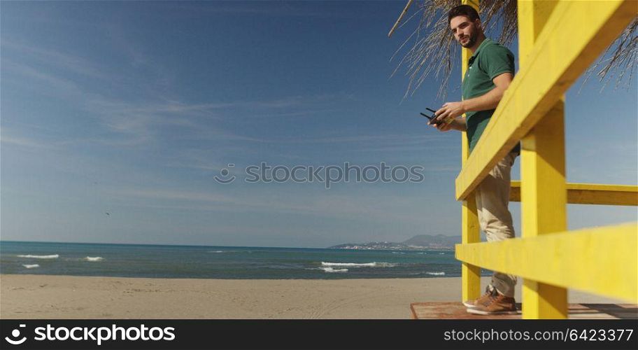Man operating drone with remote controler by the sea on autumn day