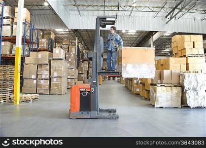 Man operating fork lift truck in distribution warehouse