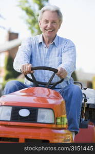 Man outdoors driving lawnmower smiling