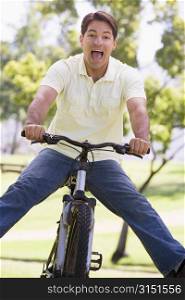 Man outdoors on bike with legs out