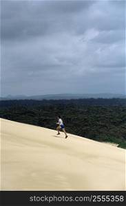 Man outdoors on sandy hill running