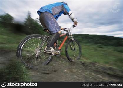 Man outdoors on trails riding bicycle (selective focus)