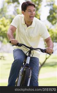 Man outdoors riding bike smiling