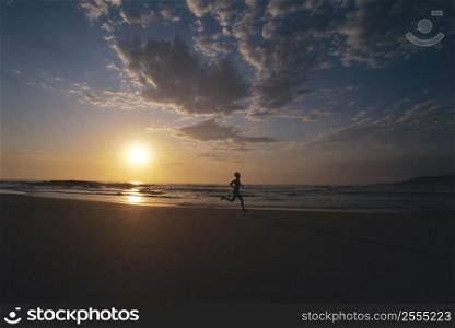 Man outdoors running on a beach at sunset (silhouette)