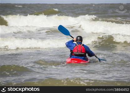 Man paddling in kayak on water of sea with waves