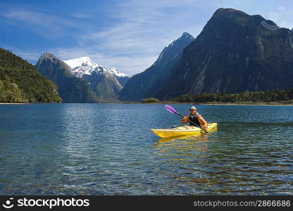 Man paddling kayak in mountain lake