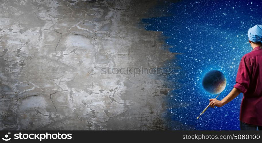 Man painter. Young handsome man painter with brush in hand. Elements of this image are furnished by NASA
