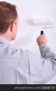 Man painting a wall white with a roller
