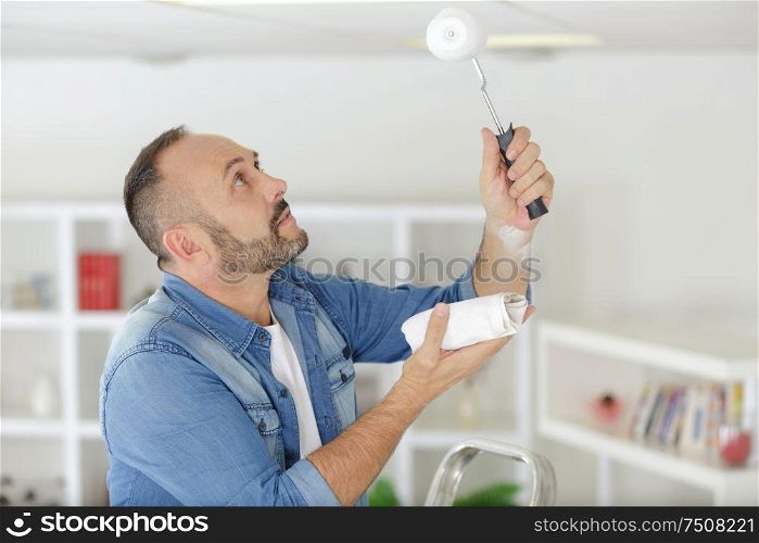 man painting ceiling in a new house
