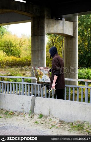 Man painting on his canvas in nature