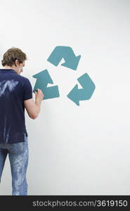 Man painting recycling sign on wall