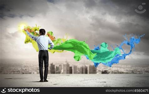 Man painting splashes. young man standing with back painting splashes against city background