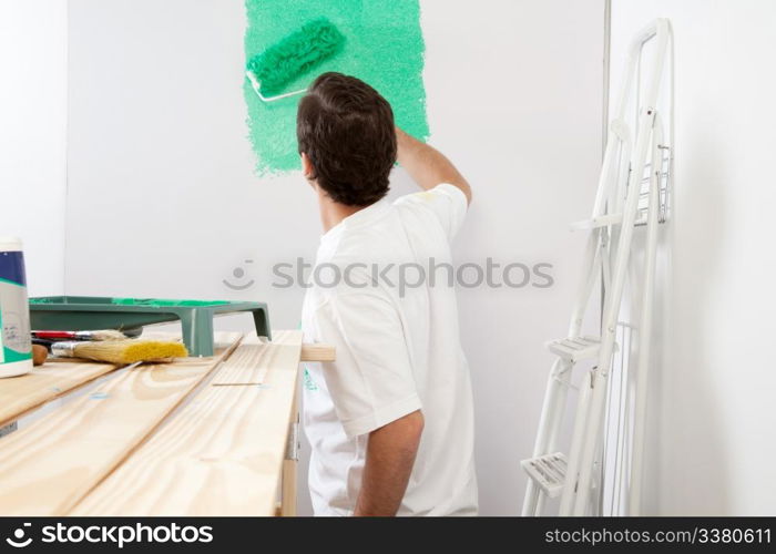 Man painting the wall with roller and brush, stepladder in background