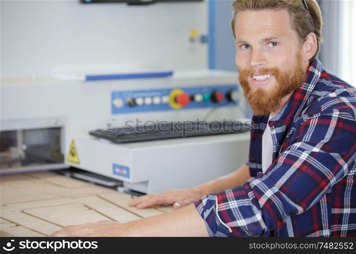 man passing wood through industrial router